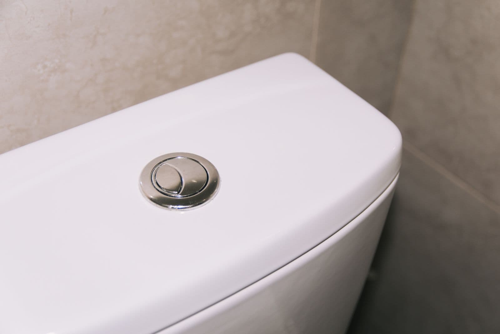 White toilet tank with a dual-flush button